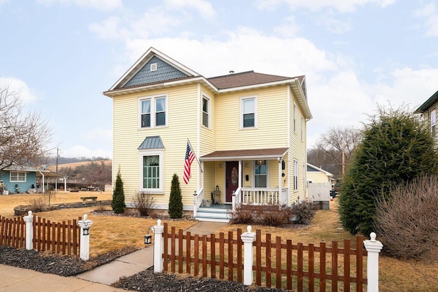 victorian-style house featuring a fenced front yard and a porch