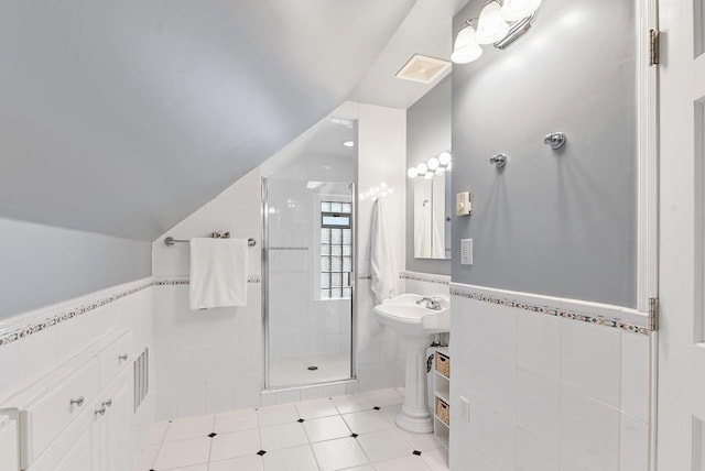 full bath featuring visible vents, tile walls, wainscoting, a shower stall, and vaulted ceiling