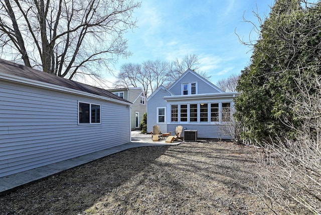 rear view of property featuring a sunroom, central AC unit, and a patio area