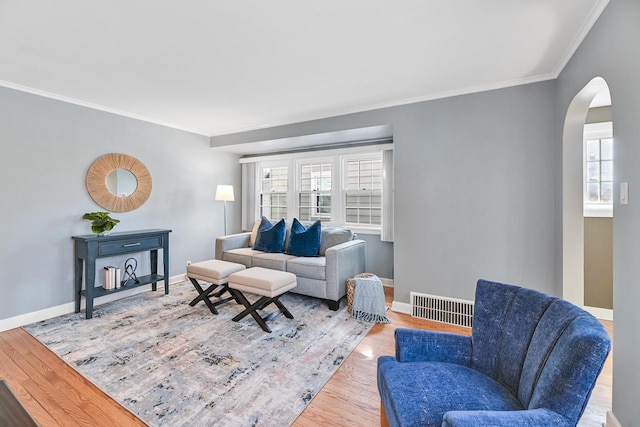 living room featuring arched walkways, visible vents, baseboards, and wood finished floors