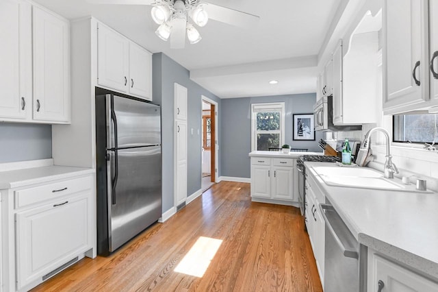 kitchen with white cabinetry, light wood-style floors, appliances with stainless steel finishes, and light countertops