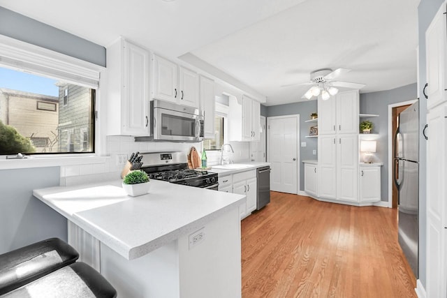 kitchen with white cabinetry, a peninsula, open shelves, and stainless steel appliances