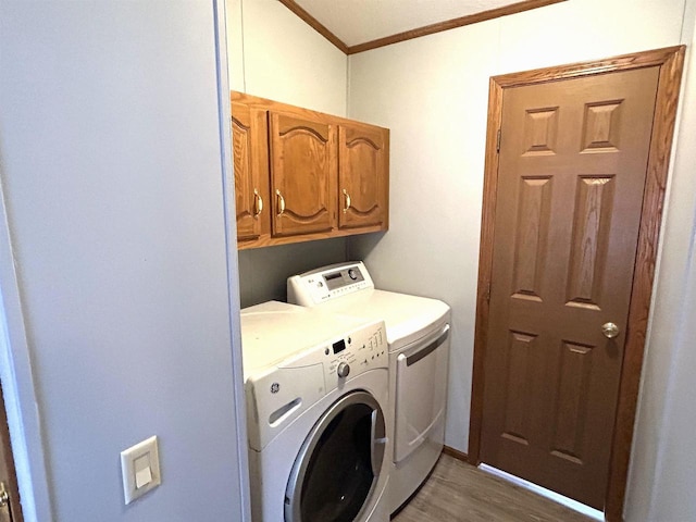 clothes washing area with ornamental molding, wood finished floors, cabinet space, and washer and dryer