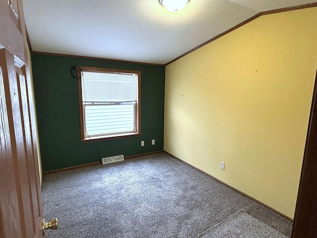 carpeted spare room featuring lofted ceiling, visible vents, crown molding, and baseboards