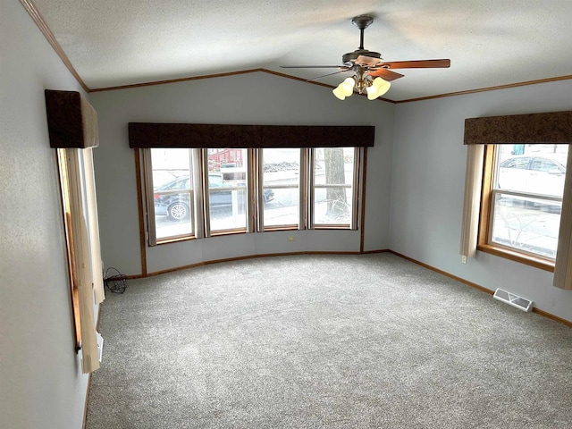 empty room with lofted ceiling, crown molding, visible vents, and a textured ceiling