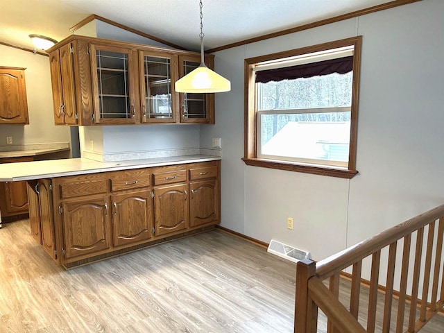 kitchen with light countertops, light wood-style flooring, glass insert cabinets, and visible vents