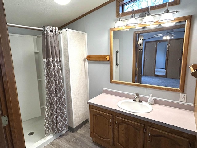 bathroom with ornamental molding, a stall shower, vanity, and wood finished floors