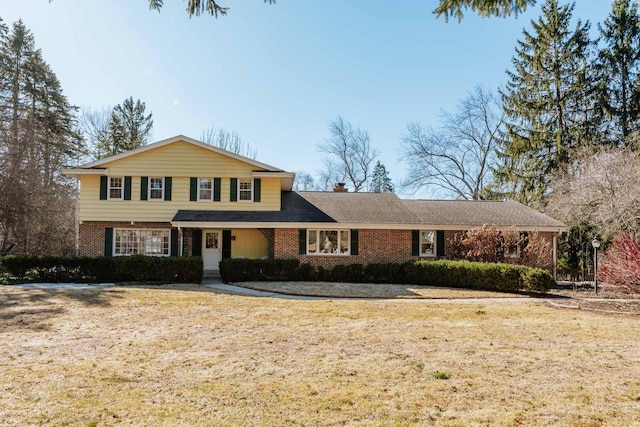 traditional home featuring brick siding, a chimney, and a front lawn