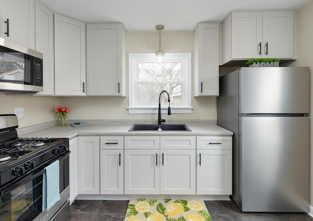 kitchen featuring appliances with stainless steel finishes, decorative light fixtures, light countertops, white cabinetry, and a sink