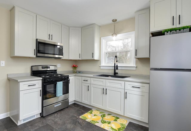 kitchen featuring white cabinets, appliances with stainless steel finishes, light countertops, and a sink