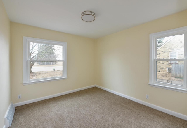 carpeted spare room with visible vents and baseboards