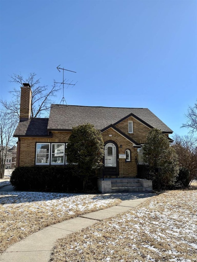 view of front of home with brick siding and a chimney