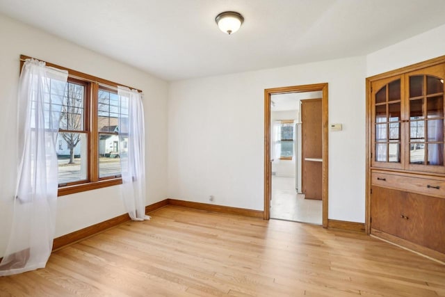 spare room featuring light wood-style floors and baseboards