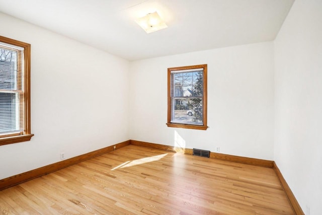 spare room with visible vents, light wood-type flooring, and baseboards