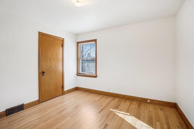 empty room featuring visible vents, light wood-style flooring, and baseboards