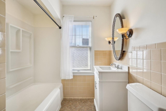 full bathroom featuring vanity, a wainscoted wall, shower / washtub combination, tile walls, and toilet