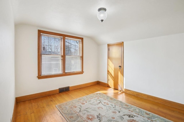 additional living space featuring visible vents, baseboards, lofted ceiling, and light wood finished floors