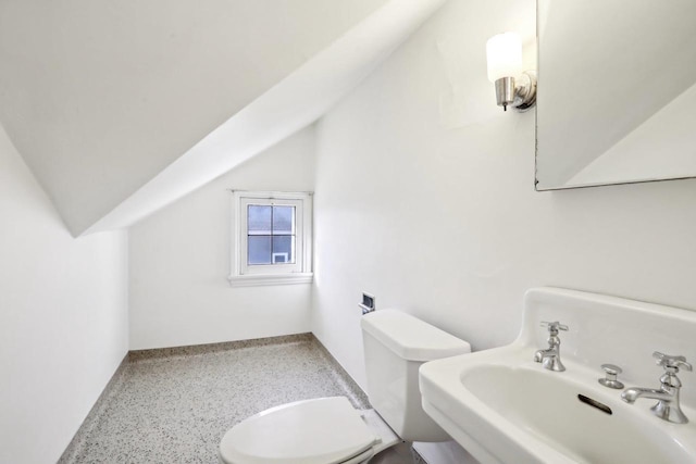 bathroom with a sink, speckled floor, lofted ceiling, and toilet