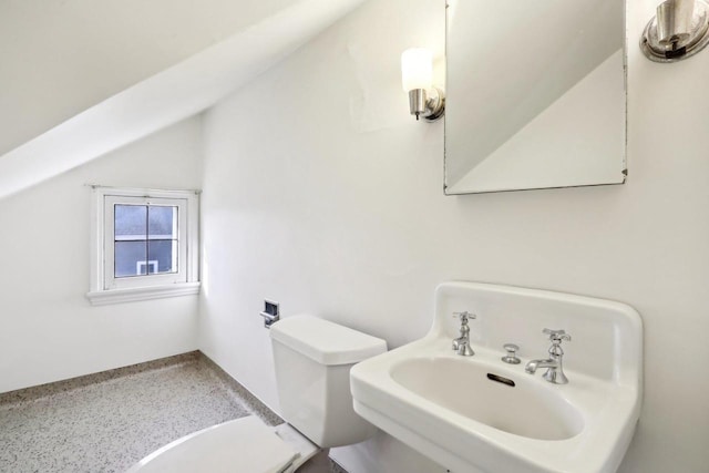 bathroom featuring vaulted ceiling, toilet, speckled floor, and a sink