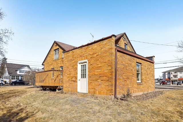 view of side of home with brick siding and a deck