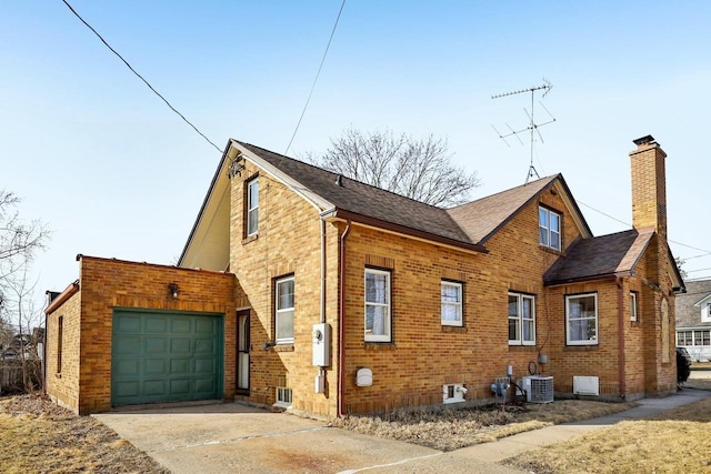 view of side of home with concrete driveway, an attached garage, brick siding, and central AC