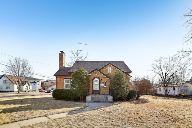 view of front of home featuring brick siding and a chimney