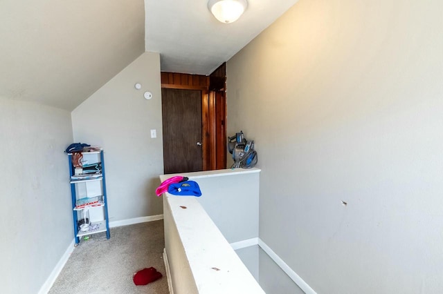 hall featuring carpet floors, lofted ceiling, and baseboards