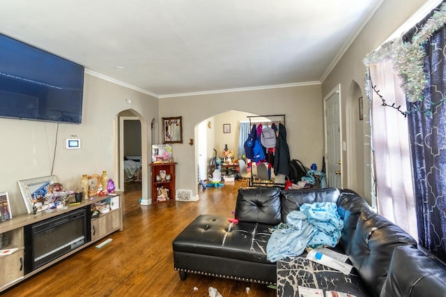 living room featuring arched walkways, a healthy amount of sunlight, crown molding, and wood finished floors