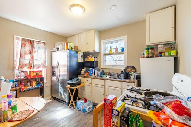 kitchen featuring black microwave, a sink, light wood-style floors, stainless steel fridge with ice dispenser, and gas range gas stove