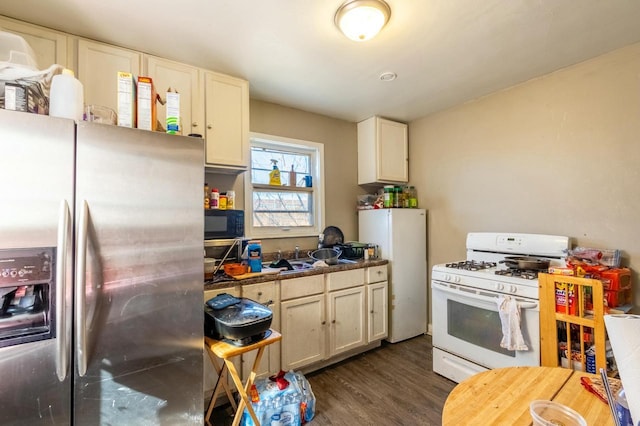 kitchen with dark wood-type flooring, white appliances, and a sink