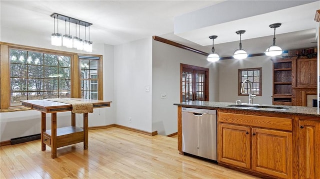 kitchen with hanging light fixtures, stainless steel dishwasher, brown cabinetry, a sink, and light wood-type flooring