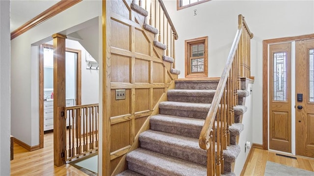 stairway with ornamental molding, plenty of natural light, ornate columns, and wood finished floors