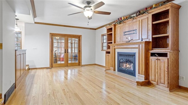 unfurnished living room with baseboards, french doors, a glass covered fireplace, and light wood-style floors