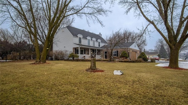 view of front facade with an attached garage, a chimney, a porch, and a front yard