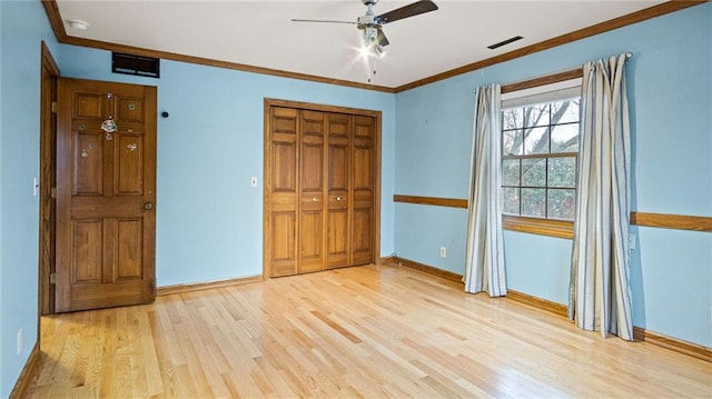 unfurnished bedroom with wood finished floors, a ceiling fan, baseboards, a closet, and crown molding