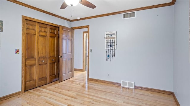 unfurnished bedroom featuring crown molding, a closet, visible vents, and light wood-style floors