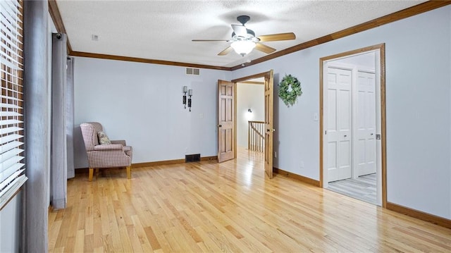 unfurnished room with light wood finished floors, a textured ceiling, visible vents, and crown molding