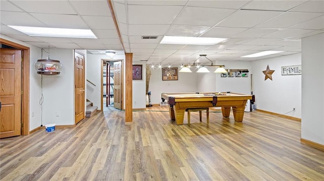 recreation room featuring baseboards, visible vents, a drop ceiling, and light wood finished floors