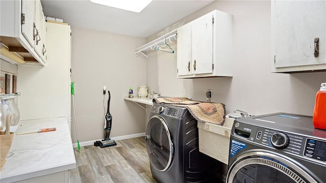 laundry room with cabinet space, baseboards, washer and clothes dryer, and light wood finished floors