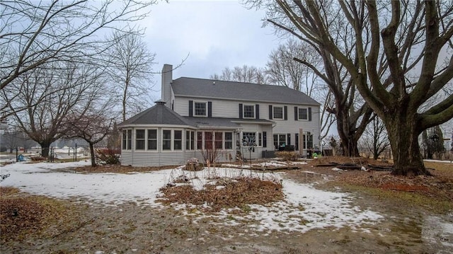 snow covered property featuring a chimney and a sunroom