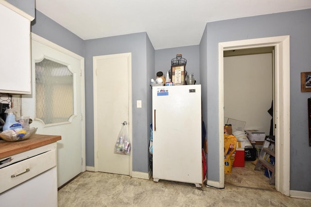 kitchen featuring freestanding refrigerator and white cabinets