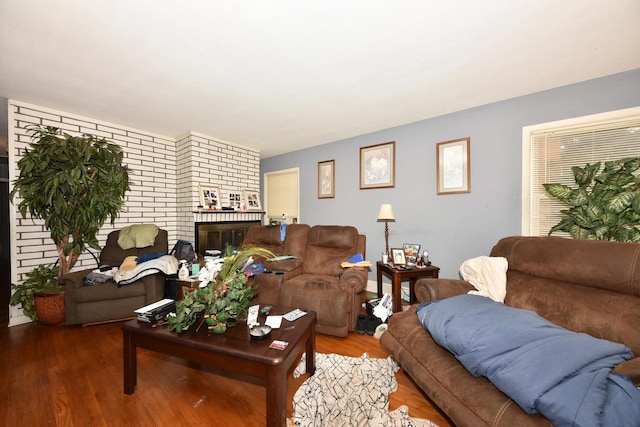 living room with a brick fireplace and wood finished floors