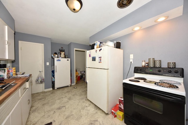 kitchen with butcher block countertops, range with electric stovetop, freestanding refrigerator, and white cabinetry