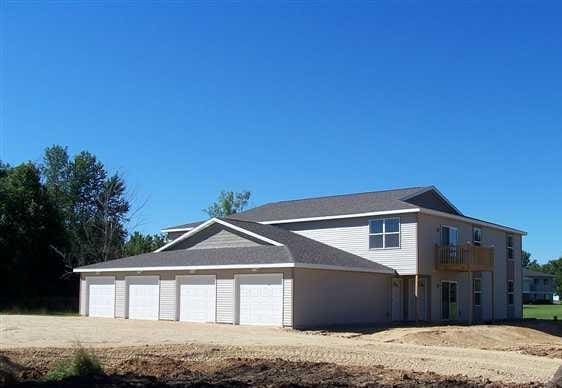 view of home's exterior with dirt driveway, an attached garage, and a balcony