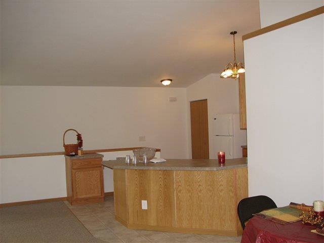 kitchen featuring a peninsula, lofted ceiling, decorative light fixtures, and freestanding refrigerator