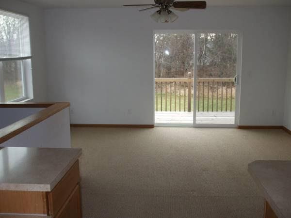 carpeted spare room featuring ceiling fan and baseboards