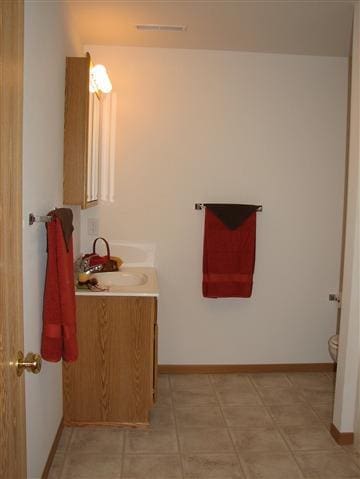 bathroom featuring toilet, vanity, and baseboards