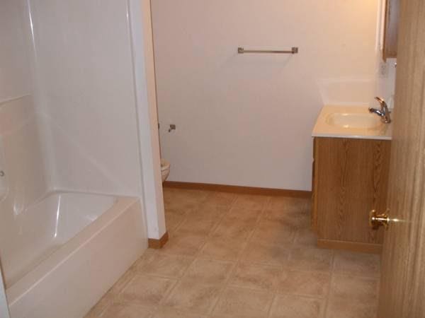 full bath with baseboards, toilet, walk in shower, vanity, and a bath