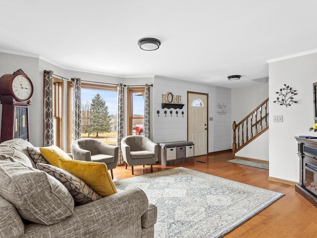 living area with baseboards, stairway, wood finished floors, and crown molding