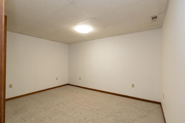 carpeted spare room featuring a paneled ceiling, visible vents, and baseboards